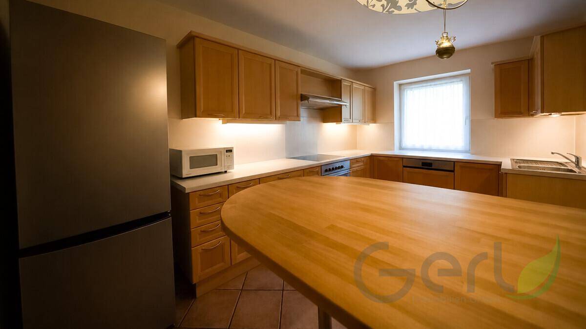 Funktionale Küche mit Holzschränken, großer Kochinsel und integrierten Geräten für den täglichen Gebrauch.