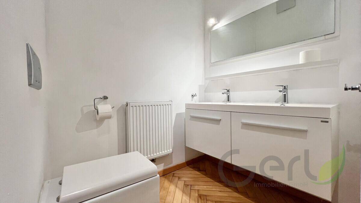 Modernes Badezimmer mit Doppelwaschbecken, Wandspiegel und hellem Ambiente.