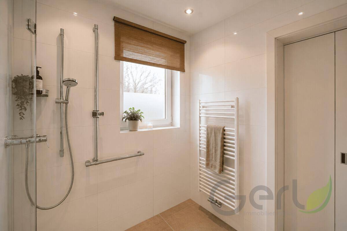 Detaillierte Ansicht der begehbaren Dusche mit Handbrause und beheiztem Handtuchhalter.