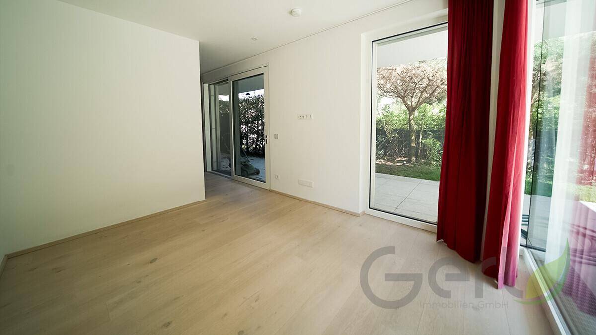 Helles, leeres Zimmer mit Holzboden und großen Fenstern, vielseitig nutzbar.