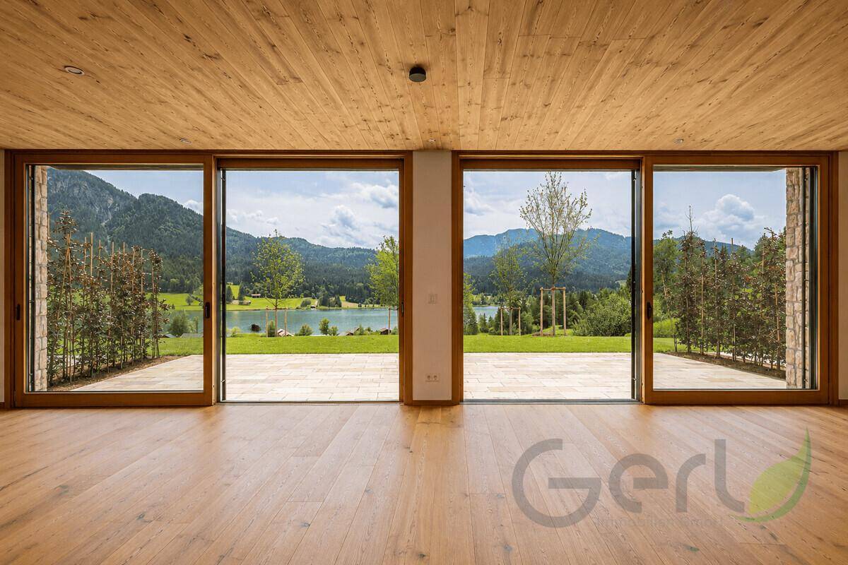 Weitläufiger Wohnraum mit Panoramablick auf den See und die umliegende Berglandschaft.