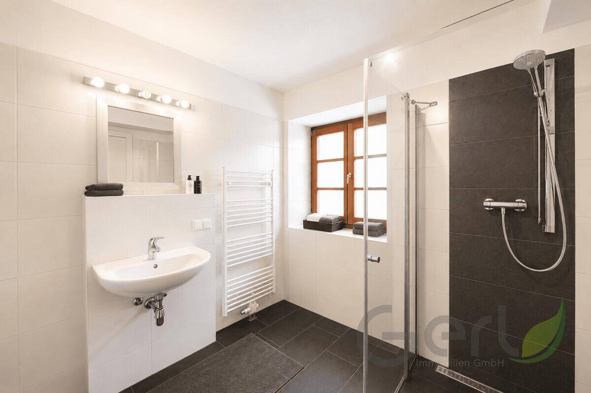 Modernes Badezimmer mit ebenerdiger Dusche, Waschbecken und beheiztem Handtuchhalter.