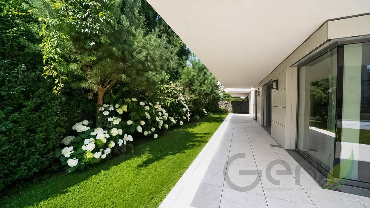 Gepflegter Gartenbereich mit Rasenfläche, blühenden Sträuchern und einer überdachten Terrasse.