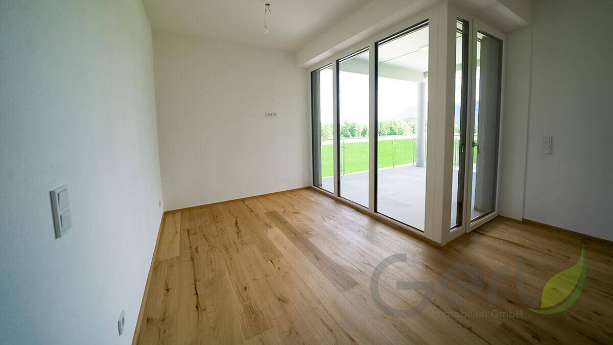 Heller, leerer Raum mit Holzfußboden und großen Glasschiebetüren, ideal als Schlafzimmer.
