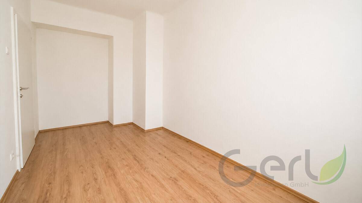 Leerer Raum mit hellem Laminatboden und weißen Wänden, bietet vielseitige Gestaltungsmöglichkeiten.