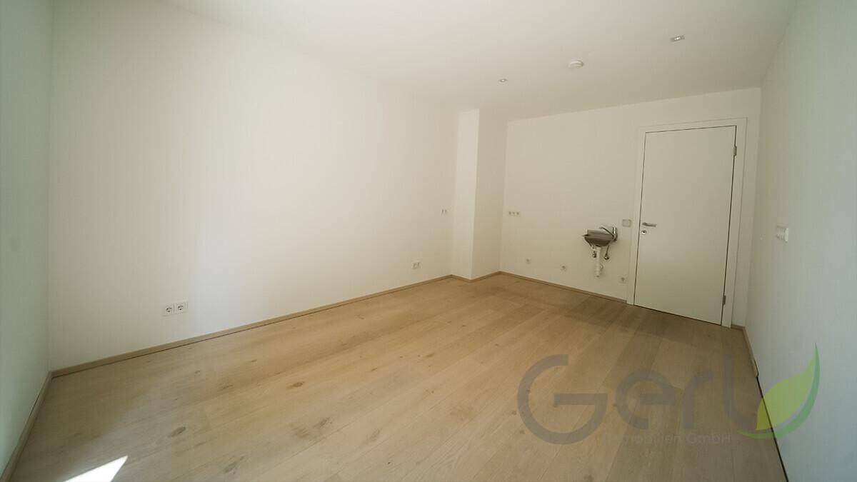 Kleiner, leerer Raum mit Waschbeckenanschluss, ideal als Gäste-WC oder Abstellraum.