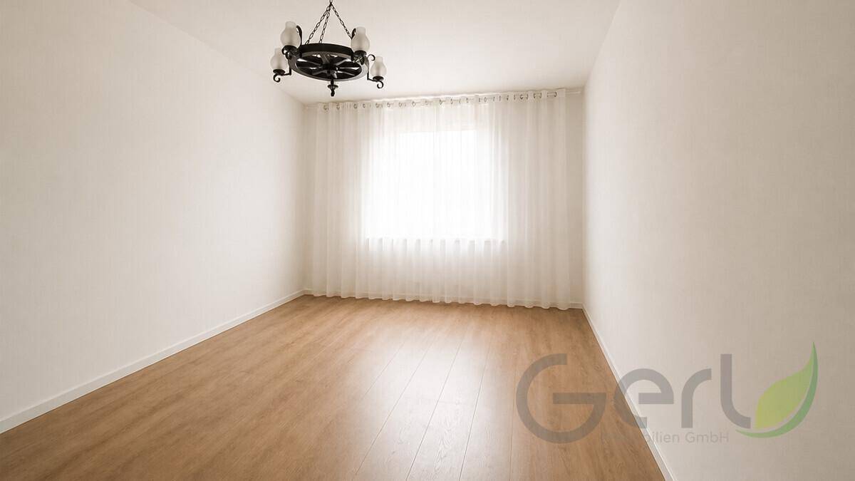 Helles, leeres Zimmer mit Laminatboden, weißen Wänden und einem Fenster mit Vorhängen.