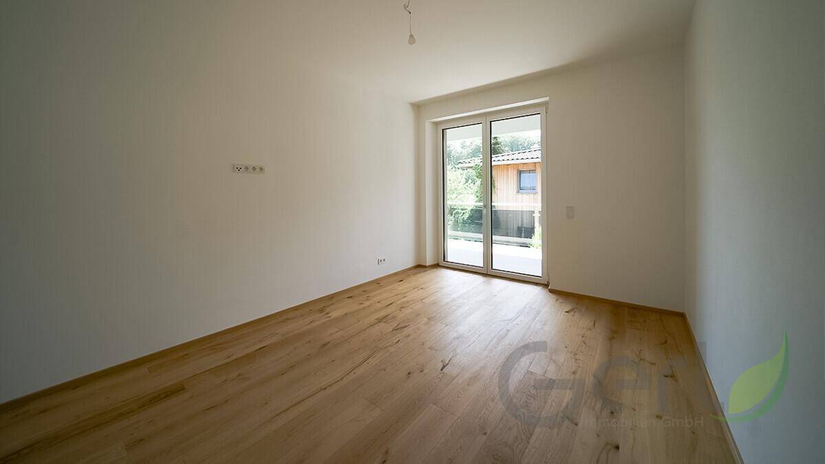 Leerer Raum mit Holzfußboden und einer Glastür, geeignet als Gäste- oder Kinderzimmer.