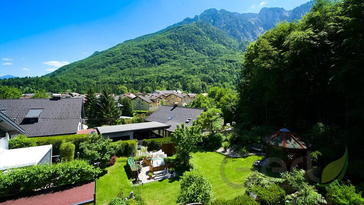 Weitläufiger Gartenbereich mit Rasenflächen, Bäumen und Blick auf die umliegende Berglandschaft.