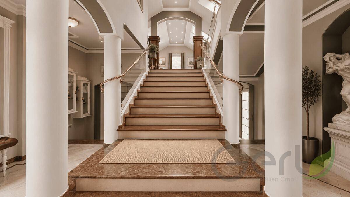 Repräsentativer Eingangsbereich mit breiter Treppe, hohen Säulen und Marmorboden in klassischem Stil.