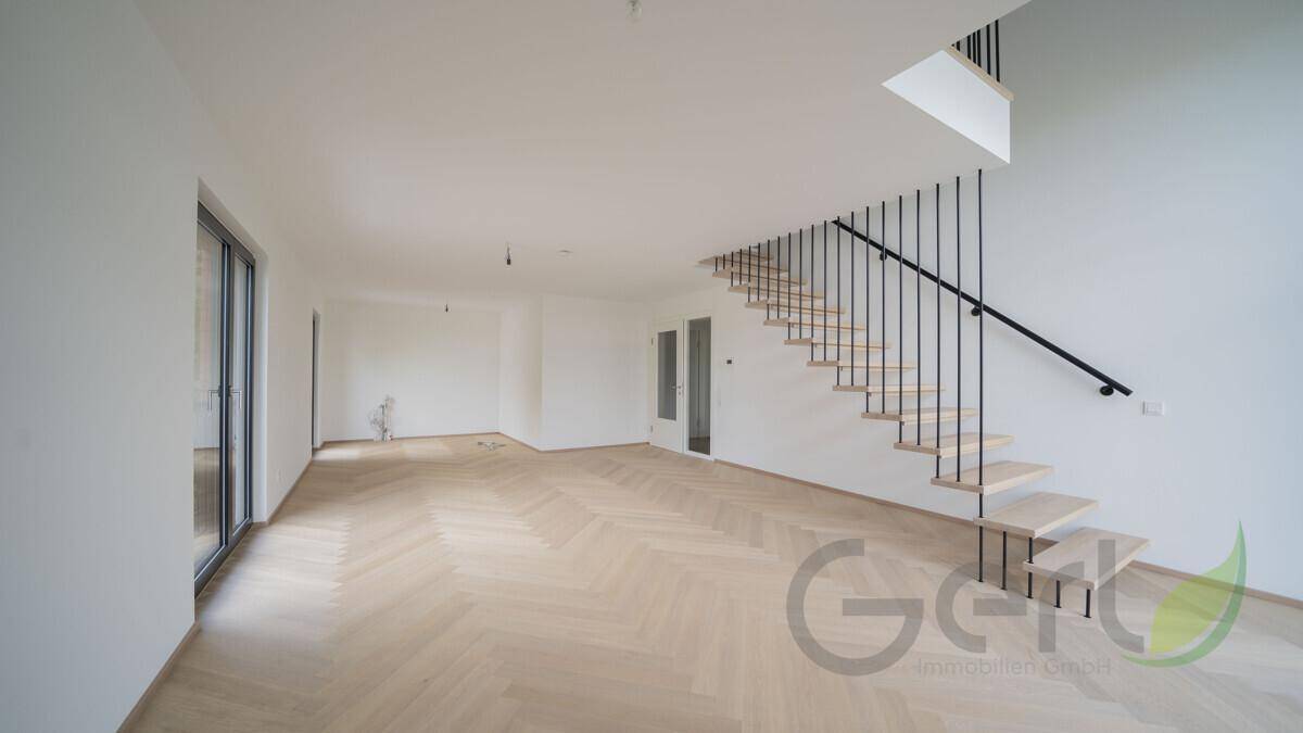 Großer, heller Wohnraum mit Fischgrätparkett, hohen Decken und Schiebetüren.