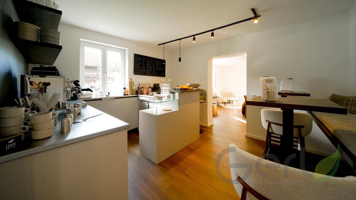 Heller Innenraum mit Holzboden, Theke und Kaffeemaschine, ideal für ein kleines Café.