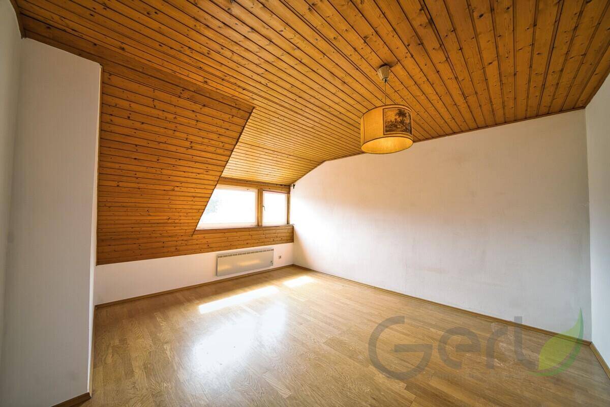 Heller Dachbodenraum mit Holzdecke, Parkettboden und Fenstern für Tageslicht.