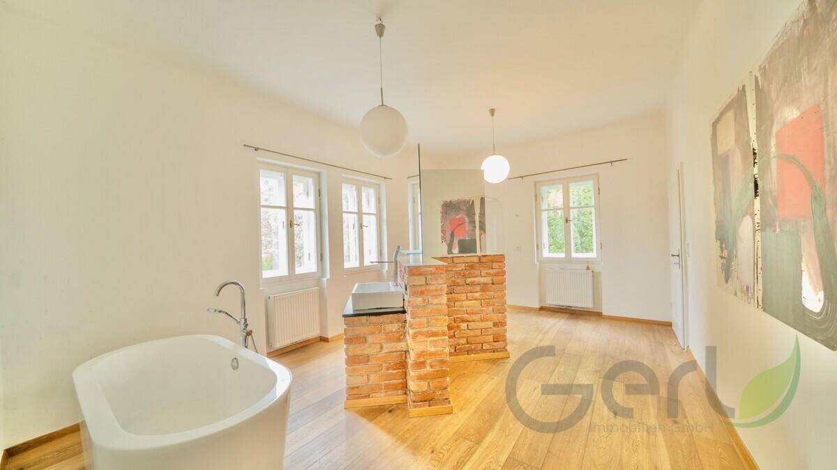 Großes Badezimmer mit freistehender Badewanne, Holzboden und viel Tageslicht.