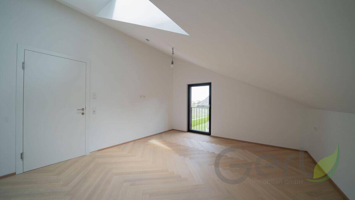 Leeres Schlafzimmer im Dachgeschoss mit Fischgrätparkett, Dachschräge und französischem Balkon.