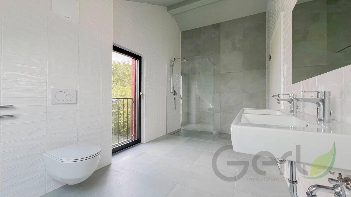 Modernes Badezimmer mit Doppelwaschbecken, begehbarer Dusche und Zugang zu einem kleinen Balkon.