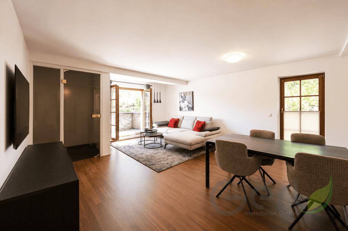 Geräumiger Wohn- und Essbereich mit Holzboden und Zugang zu einem Balkon.
