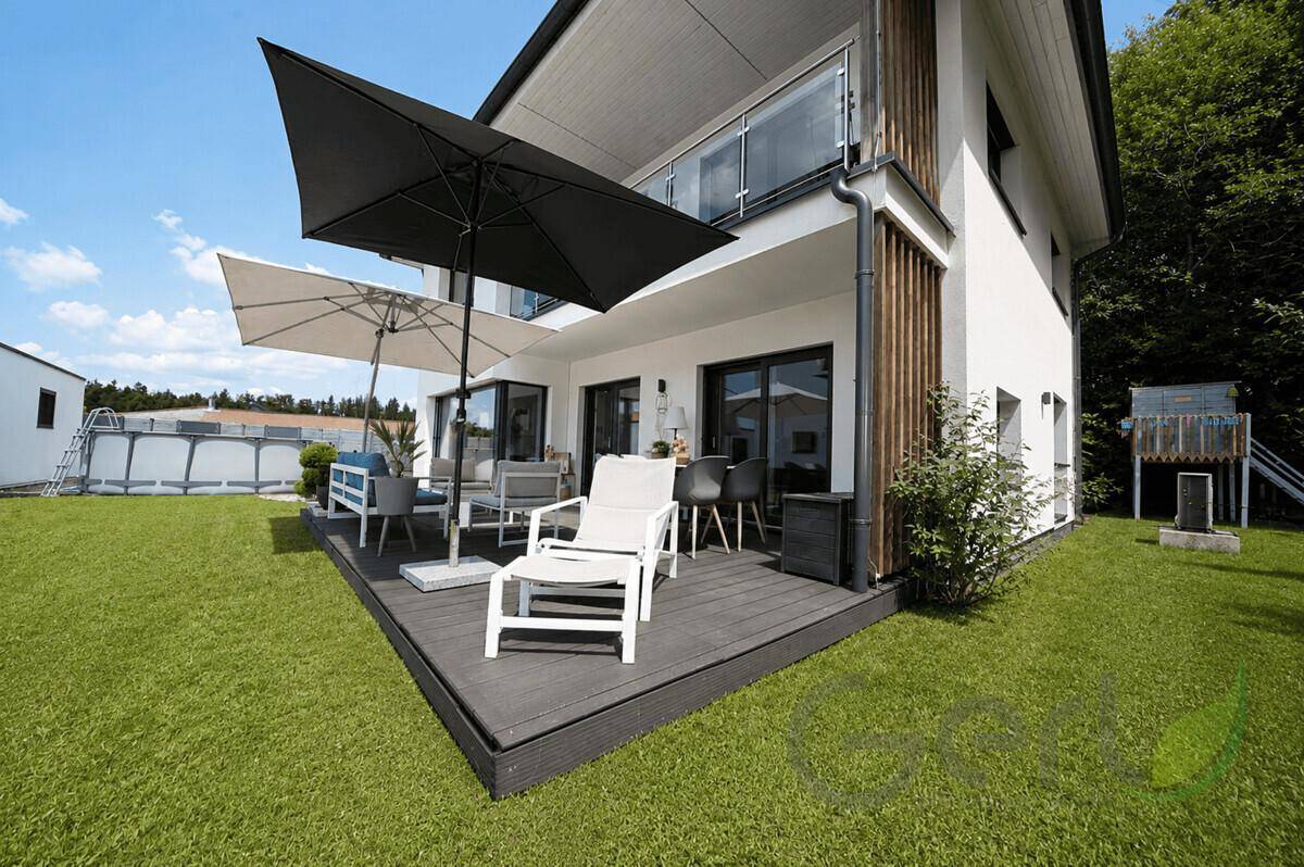 Geräumige Terrasse mit Sonnenschirmen, Gartenmöbeln und Blick in den Garten.