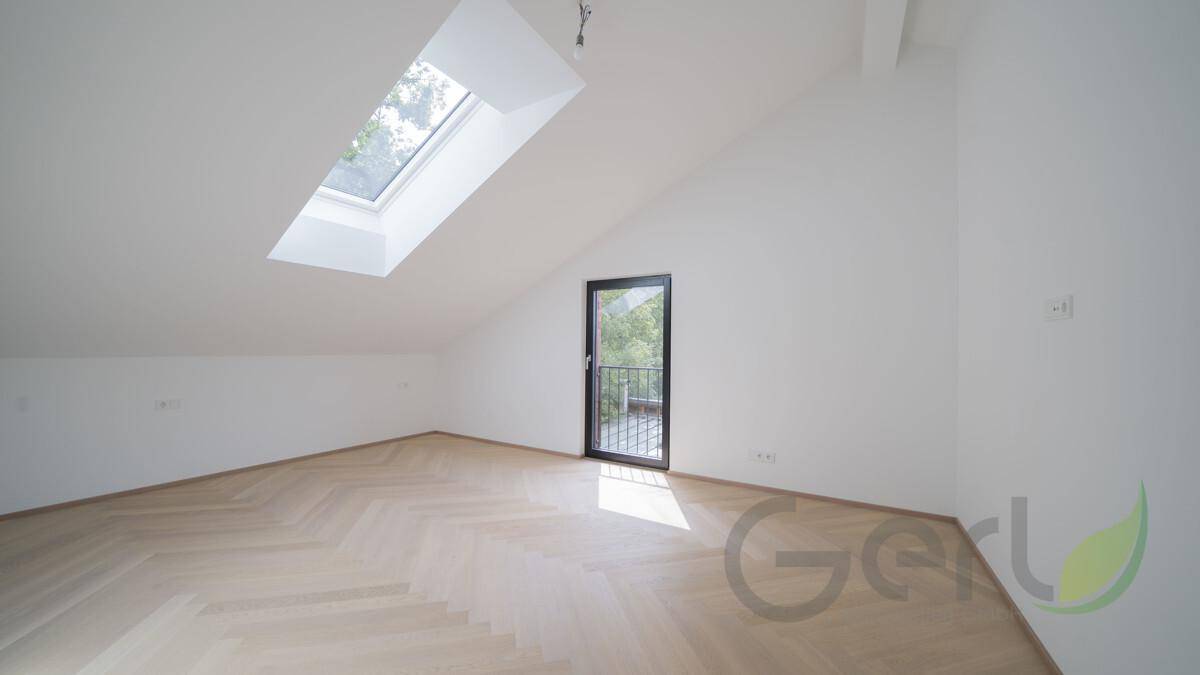Geräumiges Zimmer im Dachgeschoss mit Schrägdach, Dachfenster und Zugang zu einem französischen Balkon.