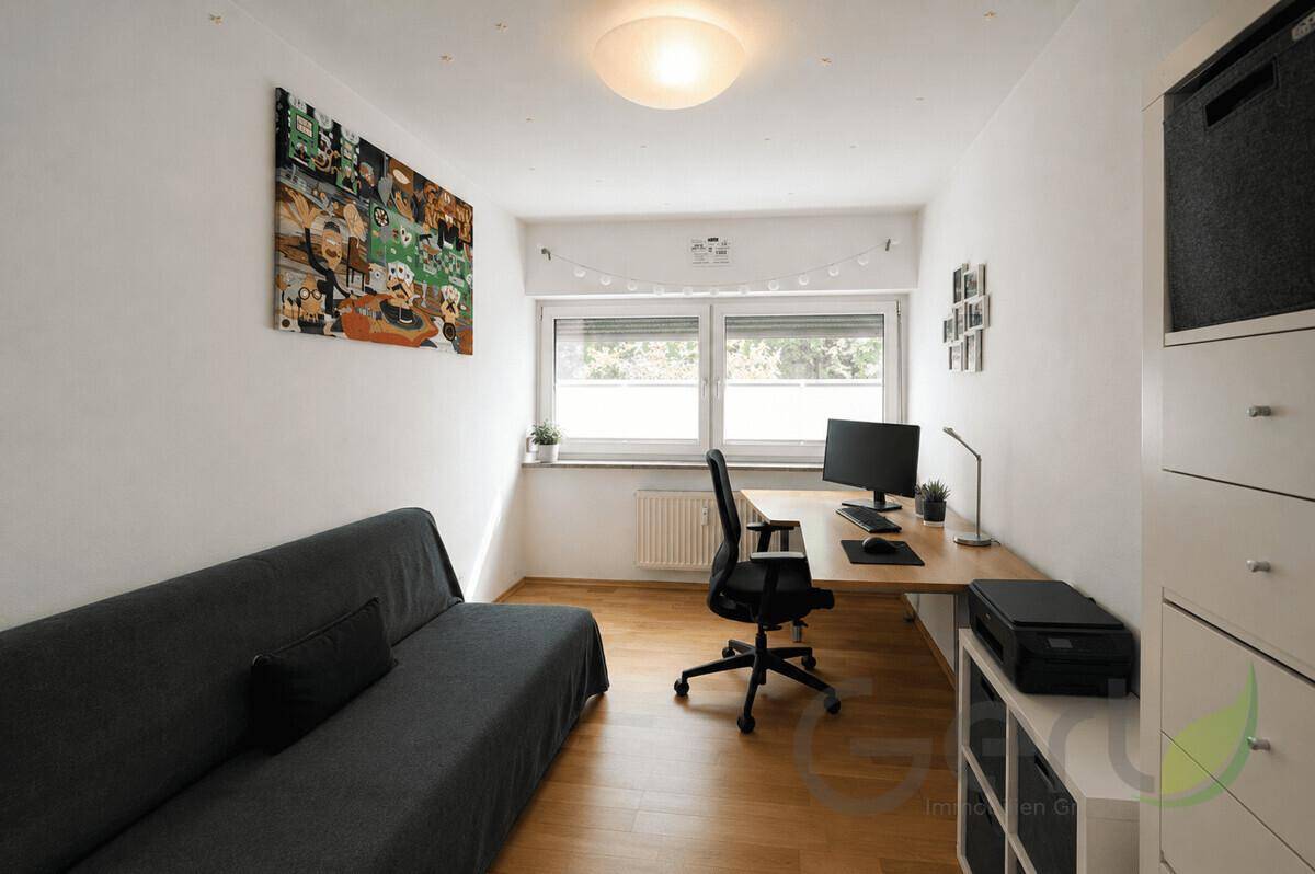 Funktionales Arbeitszimmer mit Schreibtisch, Bürostuhl und einem Schlafsofa.