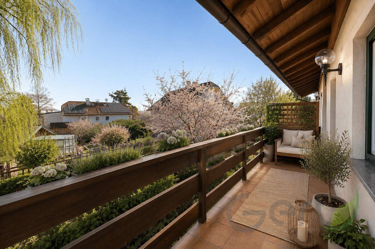 Gemütlicher Balkon mit Holzboden und Sitzgelegenheiten, umgeben von grüner Bepflanzung.