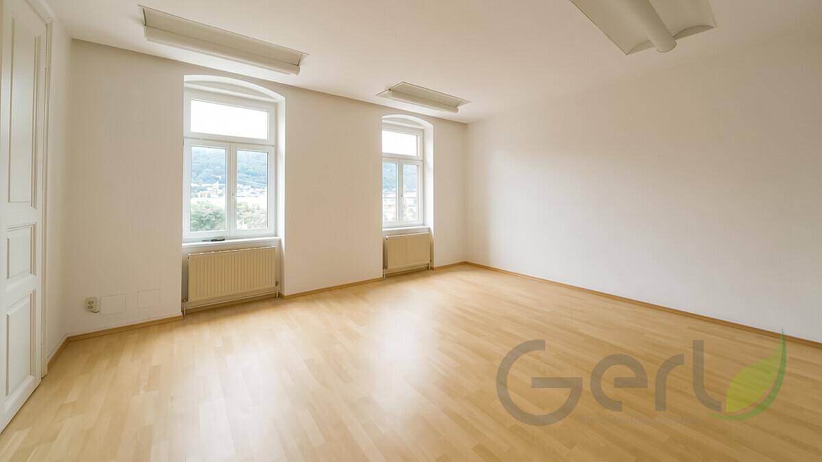 Modern eingerichtetes Büro mit Schreibtisch, bequemen Sitzgelegenheiten und viel Tageslicht durch große Fenster.