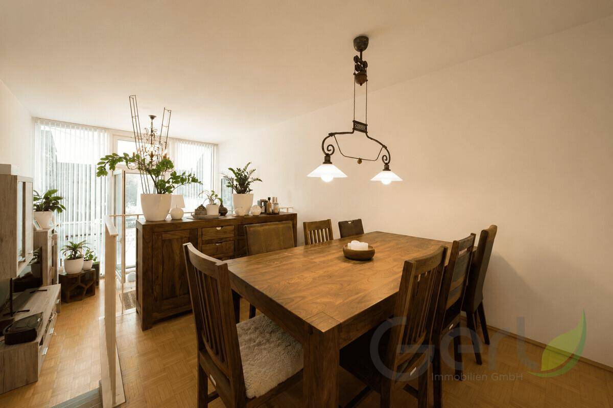 Gemütlicher Essbereich mit Holztisch und Stühlen, daneben ein Sideboard mit Pflanzen.