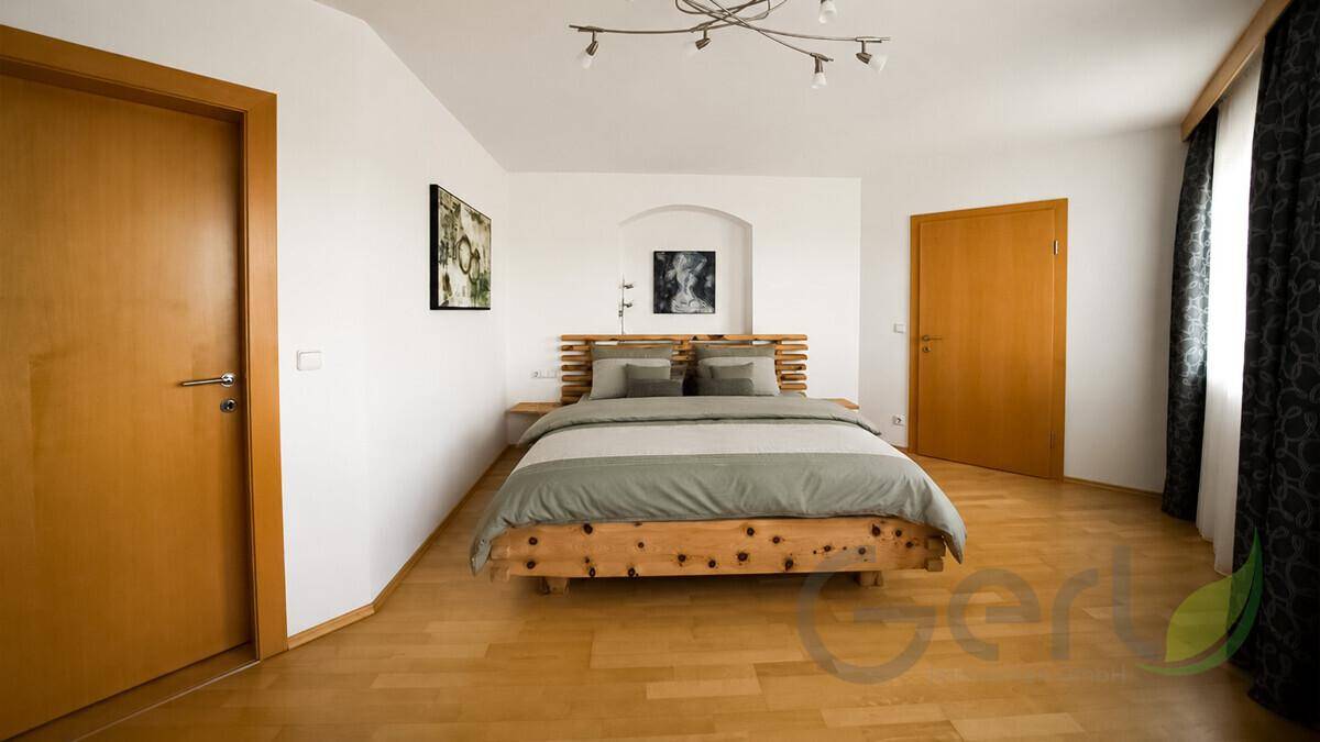 Helles Schlafzimmer mit Holzbett, weißen Wänden und Parkettboden.