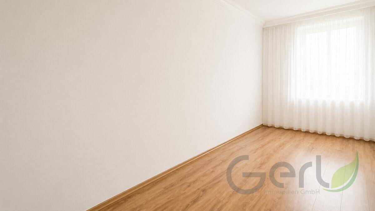 Leerer Raum mit hellem Laminatboden und weißen Wänden, bereit zur individuellen Gestaltung.