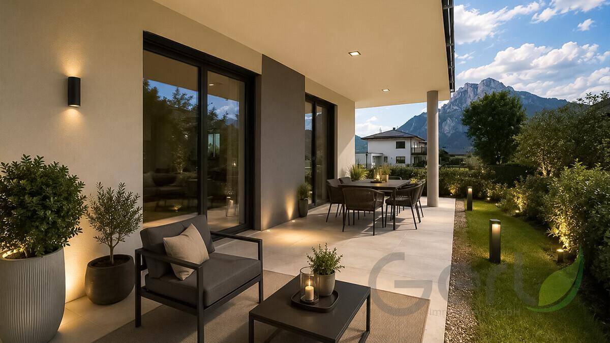 Gemütliche Terrasse mit Outdoor-Möbeln und stimmungsvoller Beleuchtung, umgeben von Bergen.