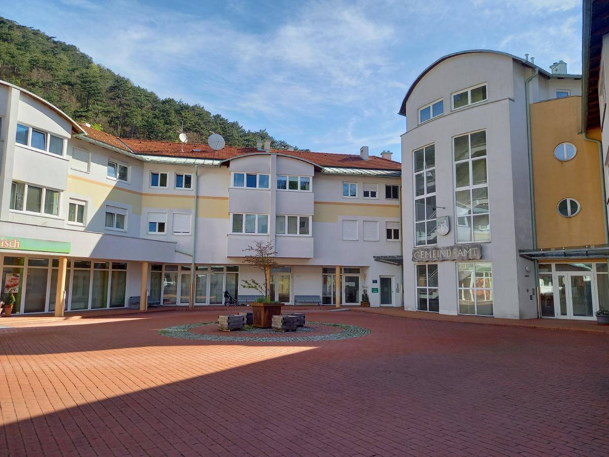 Sonniger Blick auf den Innenhof des Gemeindeamtes mit gepflastertem Bereich und umliegenden Gebäudeteilen.