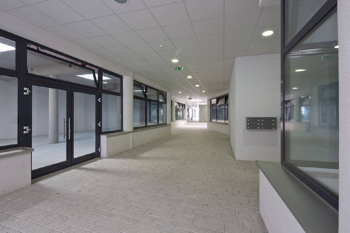Langer, heller Flur mit vielen Fenstern und Zugang zu verschiedenen Gewerbeeinheiten.