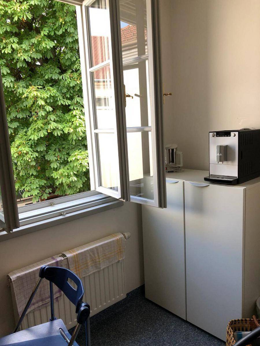 Kleiner Bereich mit Fenster, Schrank und Kaffeemaschine, ideal für eine Teeküche.