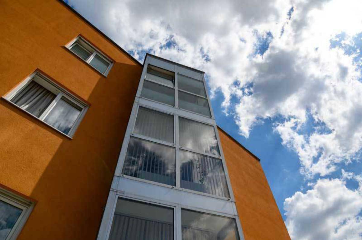 Detailansicht der orangefarbenen Fassade und des verglasten Aufzugs oder Treppenhauses des Gebäudes.