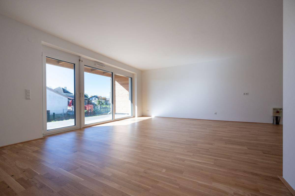 Heller, leerer Raum mit Eichenparkettboden und großen Schiebetüren zur Terrasse.