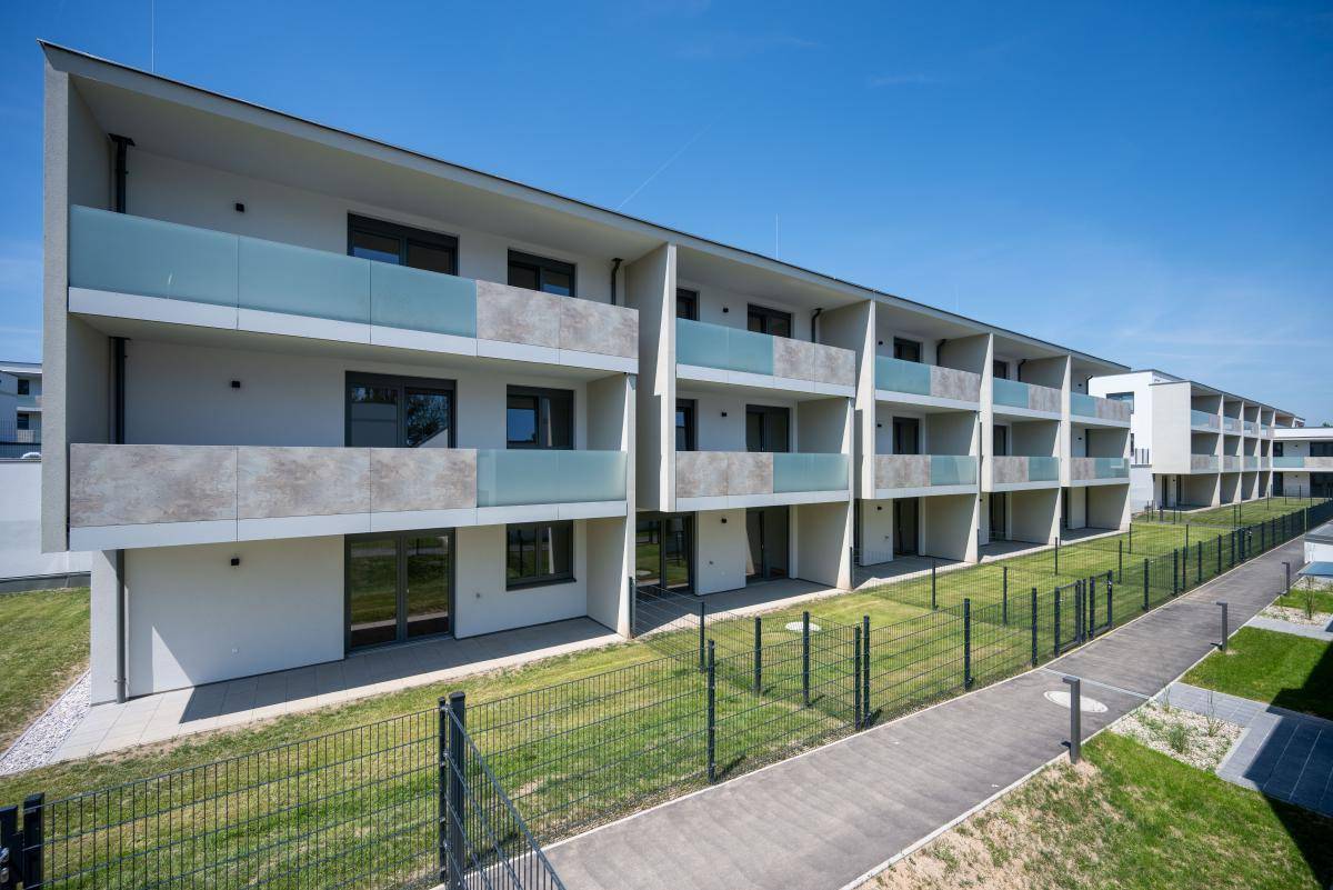 Fassade eines modernen Wohngebäudes mit Balkonen, Glasbrüstungen und Zugang zu den Erdgeschosswohnungen.