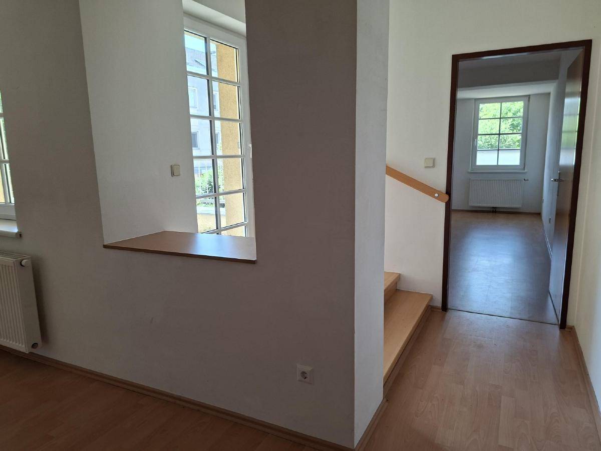 Heller Flurbereich mit Holztreppe, Holzboden und Zugang zu weiteren Räumen.