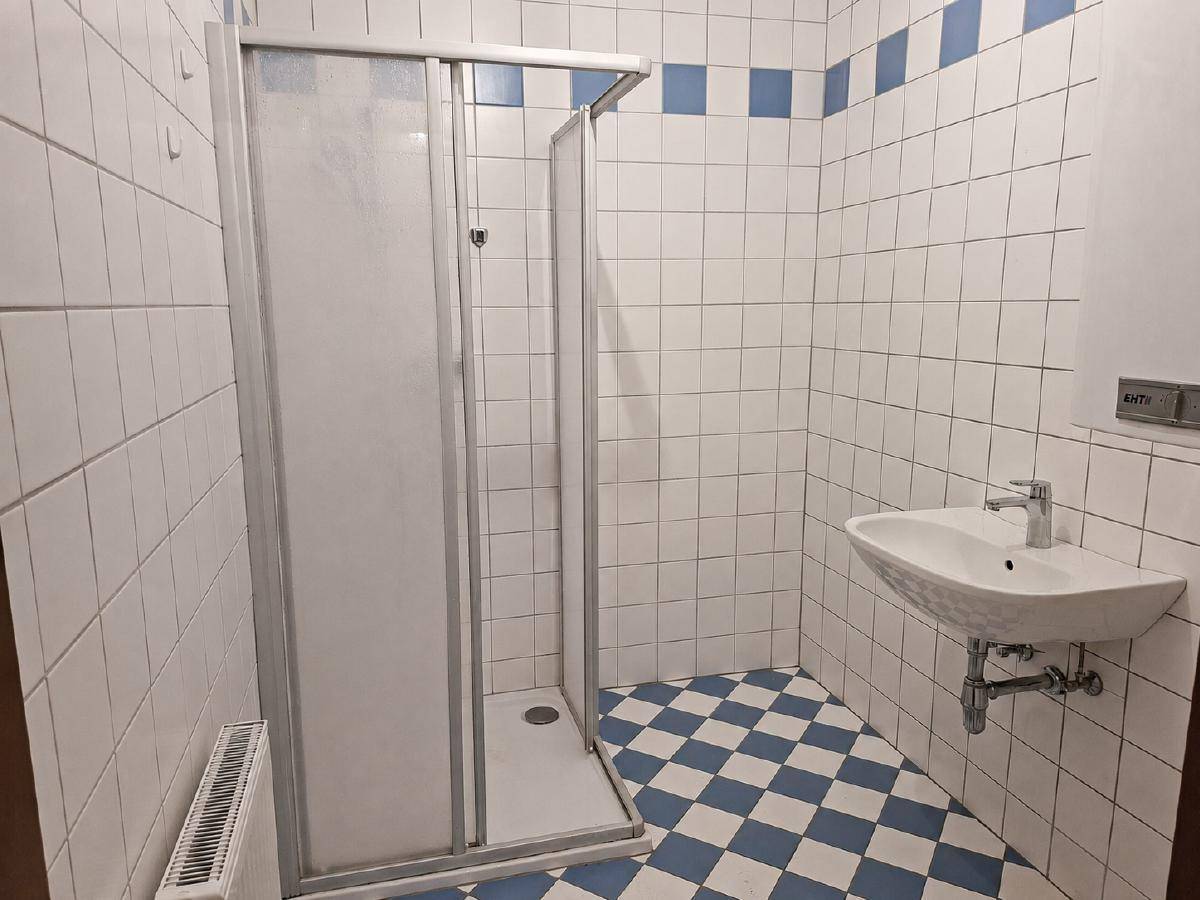 Badezimmer mit weiß-blauen Fliesen, Duschkabine und Waschbecken.