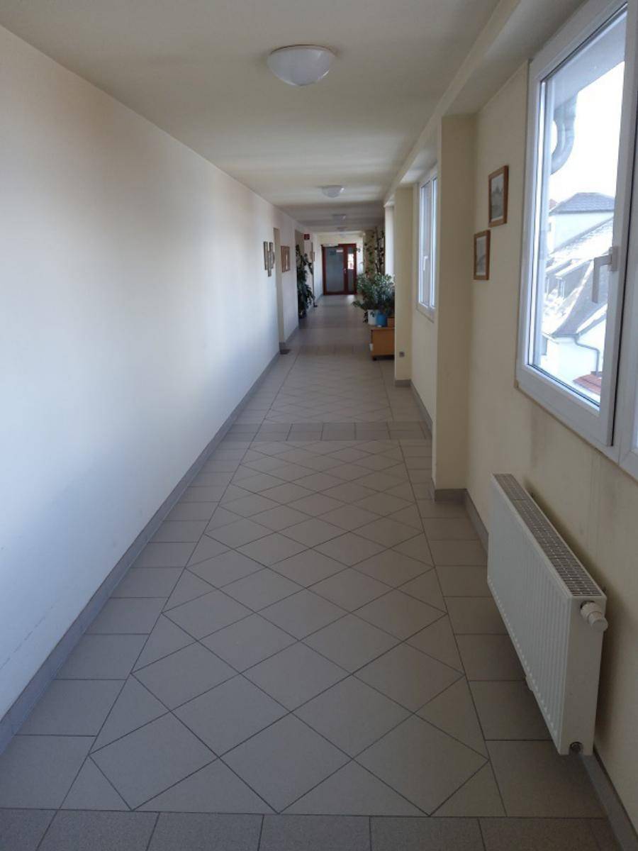Langer, heller Flur mit Fliesenboden und Fenstern, die Tageslicht hereinlassen.