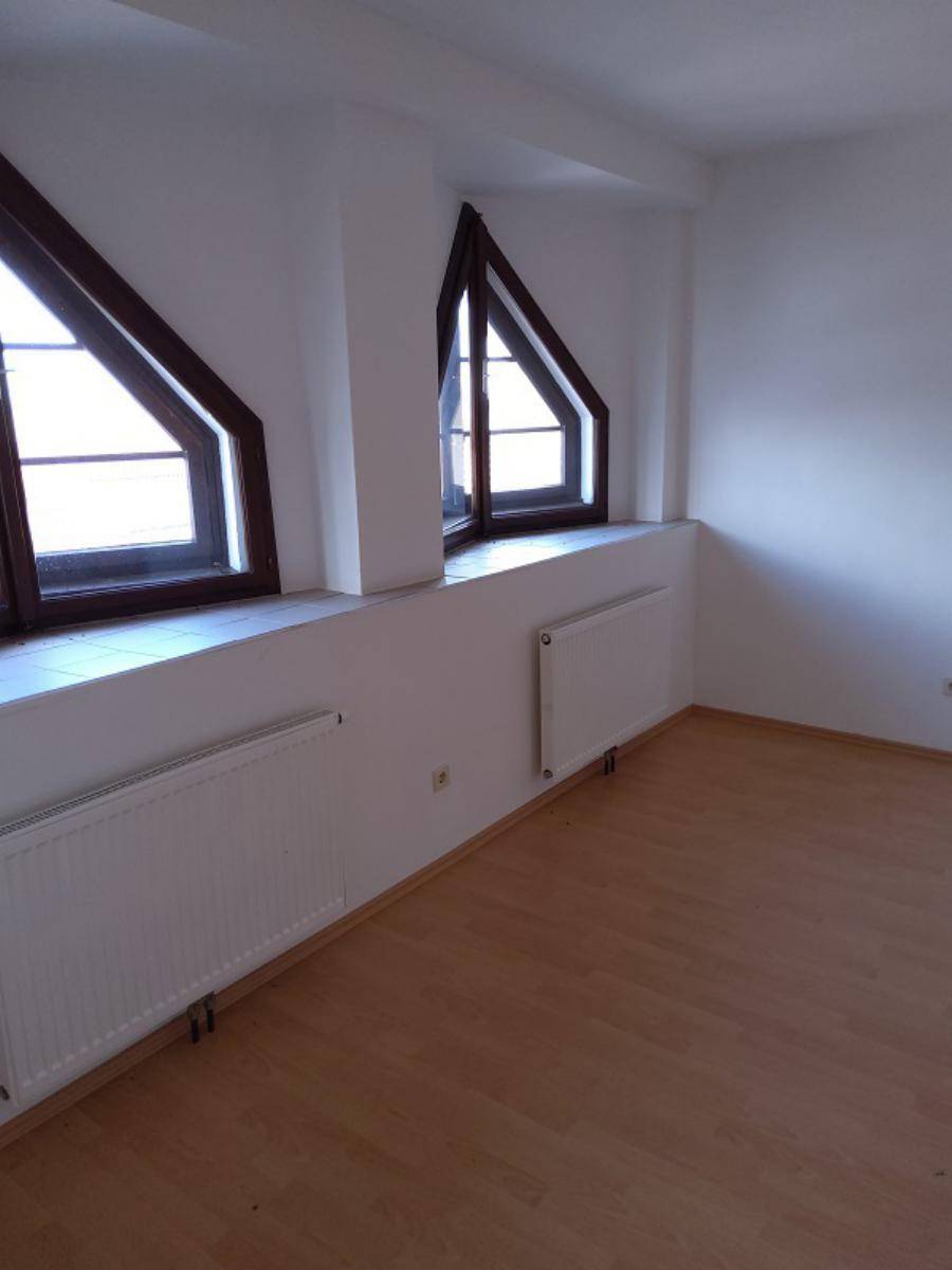 Helles Zimmer mit Laminatboden und charakteristischen Dachschrägenfenstern.