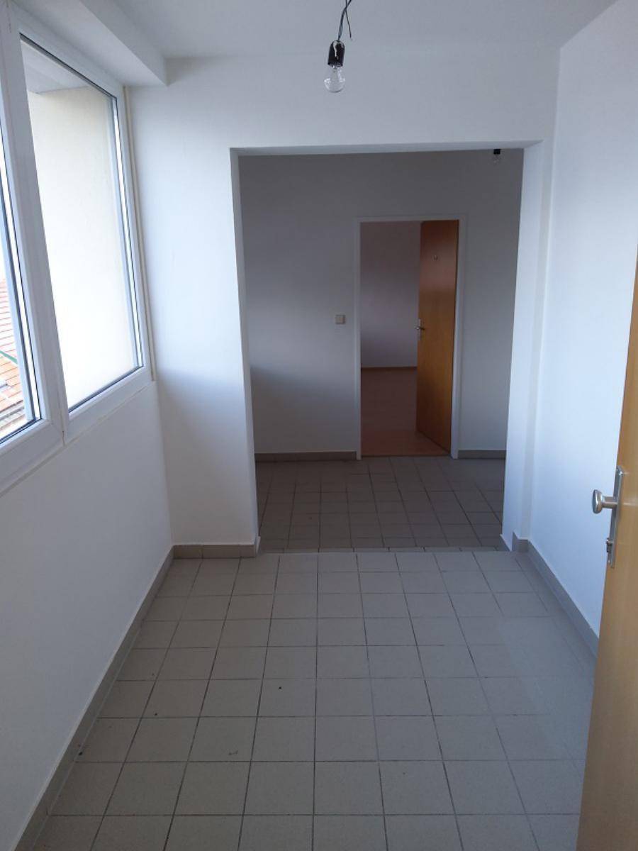 Heller Raum mit Fliesenboden und Zugang zu weiteren Zimmern.