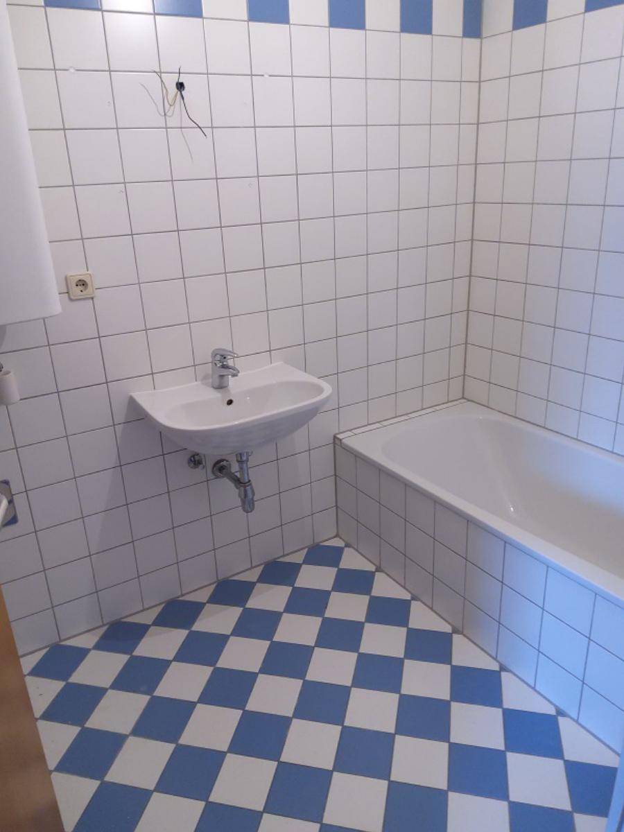 Badezimmer mit blauen und weißen Fliesen, Badewanne und Waschbecken.
