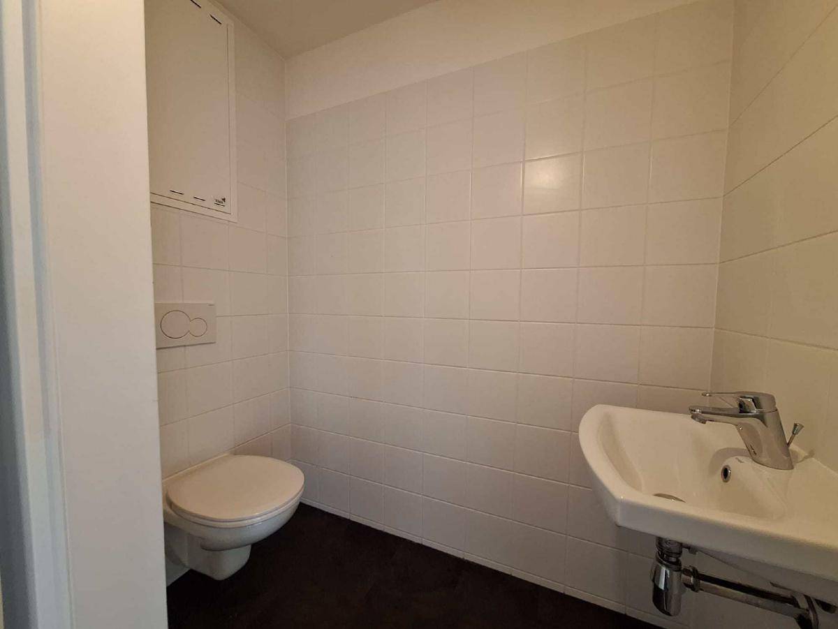 Kleines Gäste-WC mit Wand-WC, Waschbecken und weißen Wandfliesen.