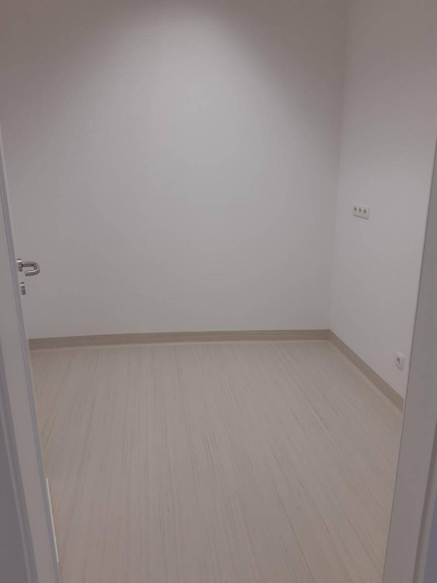Kleiner, leerer Raum mit hellem Linoleumboden und weißen Wänden, bereit zur Nutzung.