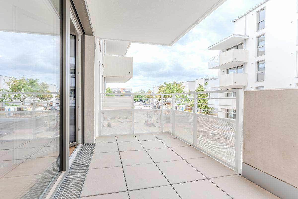Heller Balkon mit Fliesenboden und moderner Brüstung, bietet einen weiten Blick auf die Umgebung.