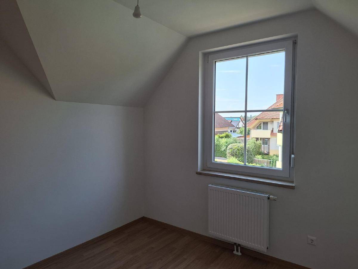Helles Schlafzimmer mit Laminatboden, Dachschrägen und Blick ins Grüne.
