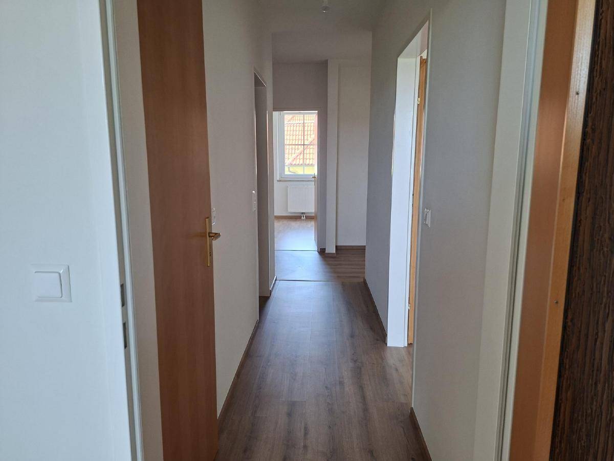 Langer, heller Flur mit Laminatboden und mehreren Türen zu angrenzenden Räumen.