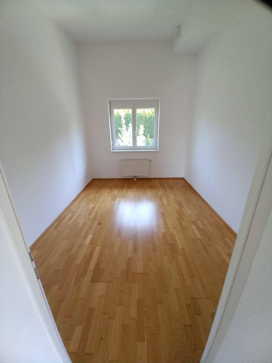 Kleineres Zimmer mit Parkettboden und einem Fenster, ideal als Kinder- oder Arbeitszimmer.