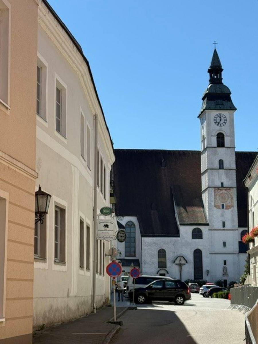 Historische Straße mit einem imposanten Kirchturm im Hintergrund unter blauem Himmel.