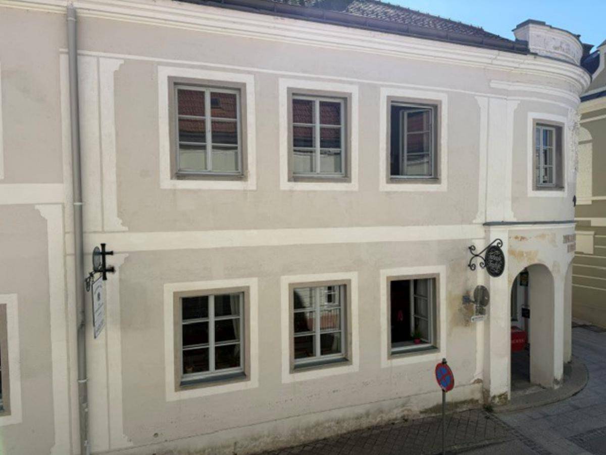 Fassade eines historischen Gebäudes mit mehreren Fenstern und einem abgerundeten Eckbereich.